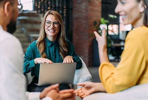Drei Personen in entspannter Unterhaltung in einem modernen Innenraum.
